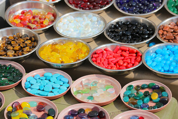 Colorful natural sea pebbles sorted in metal bowls for sale on ocean beach in Dwarka, Gujarat, India