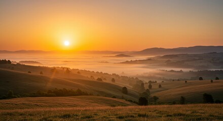 Fototapeta premium Sunrise over rolling hills and valleys, shrouded in morning mist, with golden sunlight illuminating the landscape