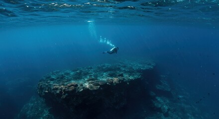 Fototapeta premium Scuba diver explores the deep blue sea over coral reefs with beams of light shining