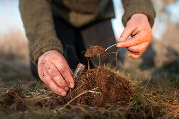 female farmer collecting soil samples in a test tube in a field. Agronomist checking soil carbon and plant health on a farm with a microscope soil test