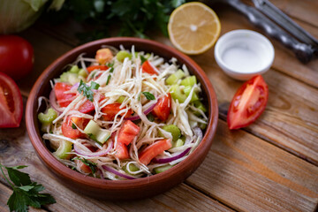 Home cooking: vegetarian salad of tomatoes, cabbage and celery for lunch. Delicious salad of fresh vegetables with olive oil for breakfast. Close-up