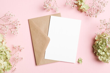 White vertical card placed on kraft paper envelope surrounded by soft baby breath and hydrangea...