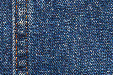 close up blue jeans texture with seam with orange thread at left side