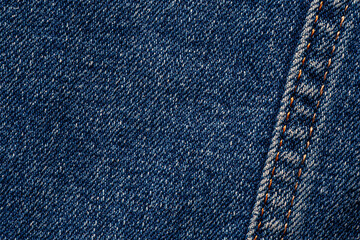 close up seam with orange thread on dark blue jeans