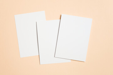 Three blank white cards on soft beige background, ideal for greeting, invitation or flyer designs presentation, wedding cards, or minimalist stationery
