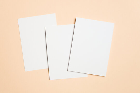 Three blank white cards on soft beige background, ideal for greeting, invitation or flyer designs presentation, wedding cards, or minimalist stationery