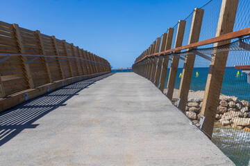 Pedestrian walkway along the Mediterranean Sea with wooden fencing in Haifa.