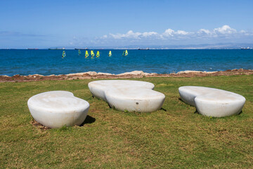 Modern white concrete benches on green grass overlooking the sea in Haifa. The embankment is named after Khulda Gurevich,.