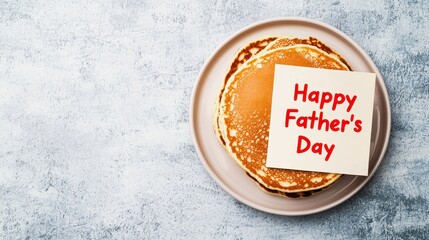 A stack of pancakes on a plate with a "Happy Father's Day" note on top, set against a textured background.