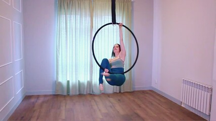 Woman dancer doing excercise on a black hoop at home