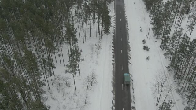 Aerial Drone Shot of Old Truck Driving Through Snowy Rural Landscape