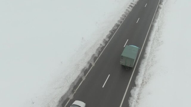 Aerial Drone Shot of Old Soviet Truck Driving Through Snowy Rural Landscape in Harsh Russian Winter