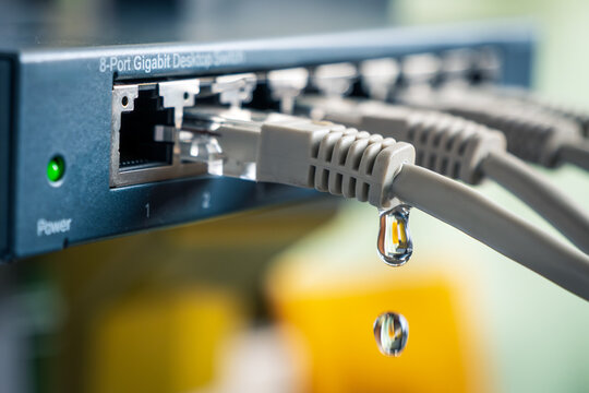 An Ethernet switch with water dripping from a network cable &mdash; symbolic representation of data leakage, cyber espionage, and hacker attacks on business networks.