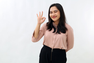 Smiling young Asian woman showing satisfied facial expression, okay hand gesture, praise and...