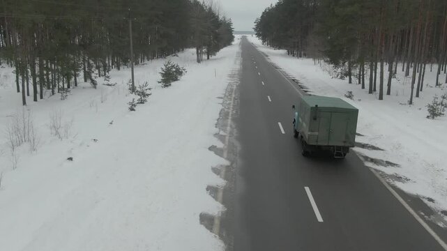 Aerial Drone Shot of Old Truck Driving Through Snowy Rural Landscape in Harsh Russian Winter