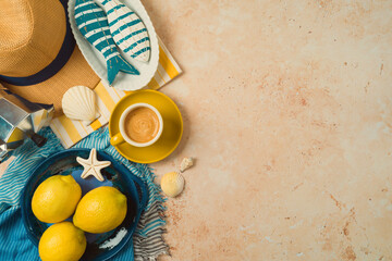 Mediterranean summer vacation concept with straw hat, lemons and coffee cup on striped towel background. Top view, flat lay