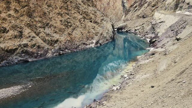 Turquoise Zanskar River meanders between colorful rocky mountains and ice patches in Ladakh&rsquo;s dramatic winter landscape