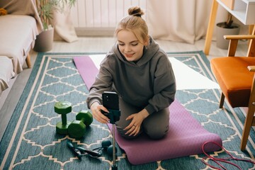 Teenager preparing online fitness lesson at home with smartphone