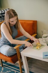 Teenager girl slicing lemon on table at home