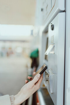 Hand of woman scanning QR code through smart phone at gas station kiosk