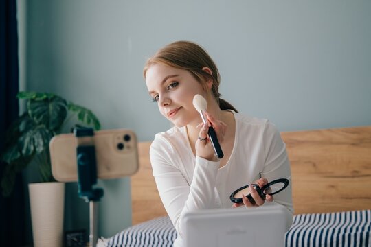 Teenager applying makeup while recording video blog at home