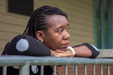 Pensive African Woman Resting on Railing Outdoors