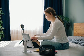 Teenager making makeup tutorial videos using smartphone and tablet at home