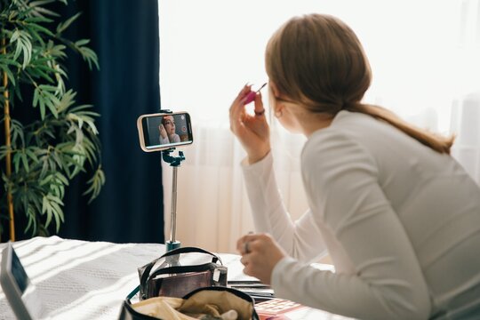 Teenager applying makeup while recording a tutorial video at home