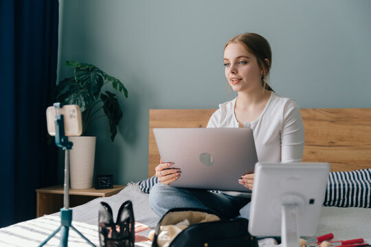 Teenager vlogger creating online content with laptop on bed