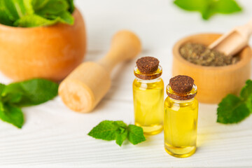 Essential oil mint on a wooden background. Peppermint essential oil with fresh mint leaves. A bottle of aromatherapy oil. Mint extract. The concept of natural cosmetics, spa care. copy space