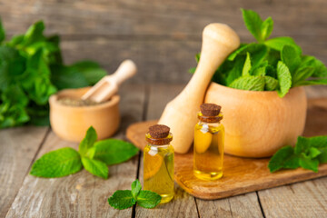 Essential oil mint on a wooden background. Peppermint essential oil with fresh mint leaves. A bottle of aromatherapy oil. Mint extract. The concept of natural cosmetics, spa care. copy space