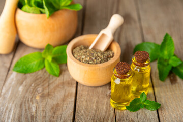 Essential oil mint on a wooden background. Peppermint essential oil with fresh mint leaves. A bottle of aromatherapy oil. Mint extract. The concept of natural cosmetics, spa care. copy space