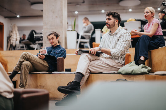 Group of people in a creative workspace engaging in casual discussions and note-taking. The atmosphere reflects collaboration and innovative team building in a modern business environment.