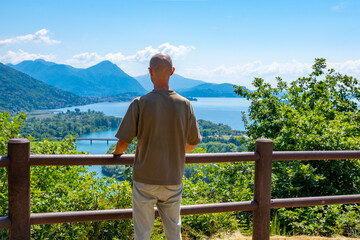 young man Exploring Lake Maggiore, Tourist enjoys leisurely walk along Montorfano village, Hiking mountain view, Italian lakeside town