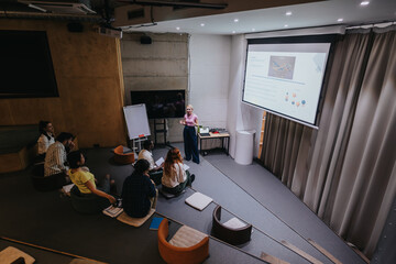 A professional seminar featuring a presentation on a screen in a stylish conference room, attended...