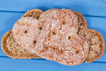Fresh homemade wholegrain bread in shape of heart for breakfast. Blue boards
