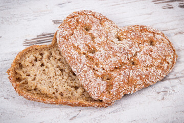 Fresh homemade wholegrain bread in shape of heart for breakfast. Old rustic background