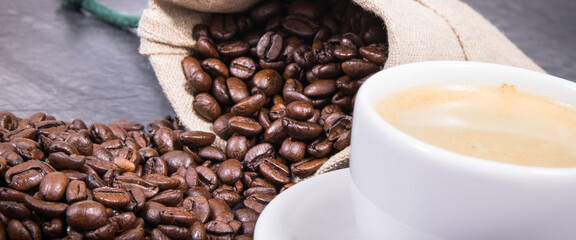 Coffee in white cup and roasted dark coffee beans in bag
