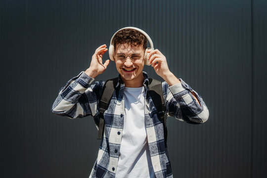 Portrait of a young adult man student smile with wireless headphones
