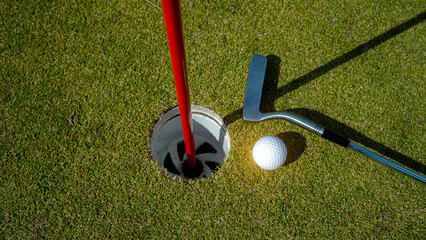 Golf hole on a green grass in the evening golf course with sunshine background.