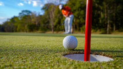Blurred Golfer putting ball on the green golf, lens flare on sun set evening time.