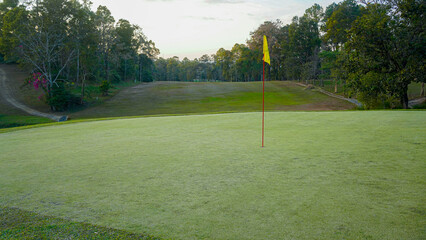 Green grass and woods on a golf field. View of Golf Course with beautiful putting green.