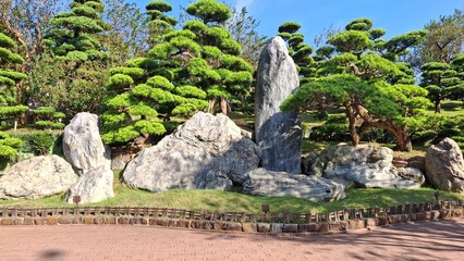 Decorative landscape with shaped pine trees and natural rock formations, reflecting principles of balance and harmony.