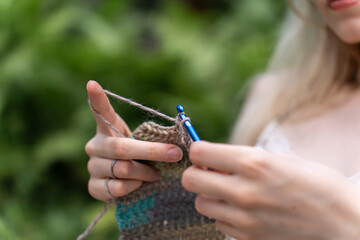 Close-up of woman hands crocheting against a nature background
