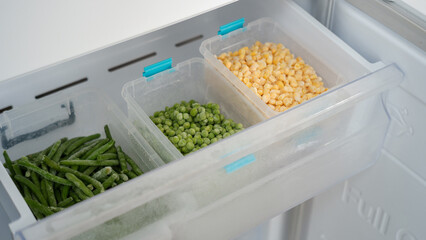 Frozen vegetables preserving freshness in refrigerator drawer: peas, corn, and green beans
