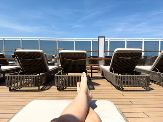 A person on a lounge chair on the a cruise ship overlooking the ocean.