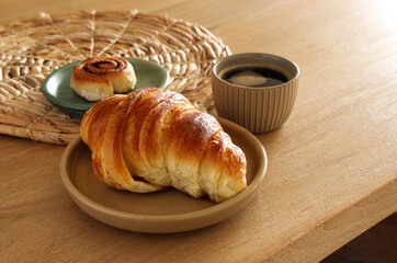 Breakfast view a bunch of croissant and a cup of coffee with cafe vibe background. Cafe menu, breakfast. Fresh pastries: croissants, rolls.