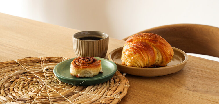 Breakfast view a bunch of croissant and a cup of coffee with cafe vibe background. Cafe menu, breakfast. Fresh pastries: croissants, rolls.