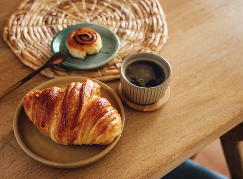 Breakfast view a bunch of croissant and a cup of coffee with cafe vibe background. Cafe menu, breakfast. Fresh pastries: croissants, rolls.