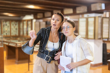 Museum female visitor with adolescence daughter walk through exhibition halls museum. Female...